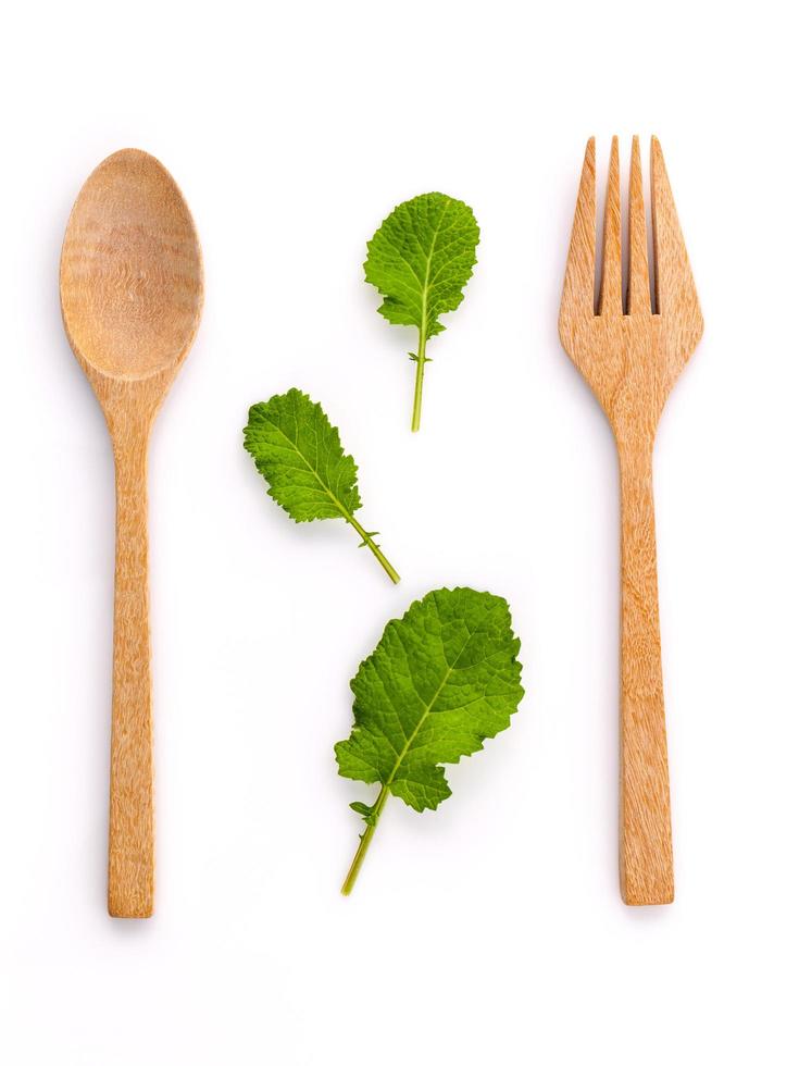 hojas verdes con cuchara y tenedor de madera foto