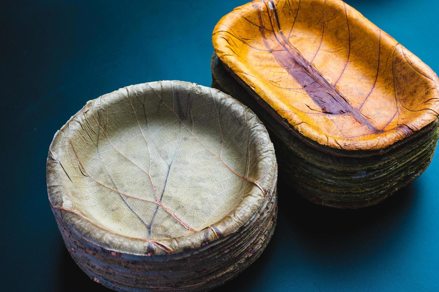 Stack of biodegradable eco-friendly paper plates next to stack of bowls made of leaves photo