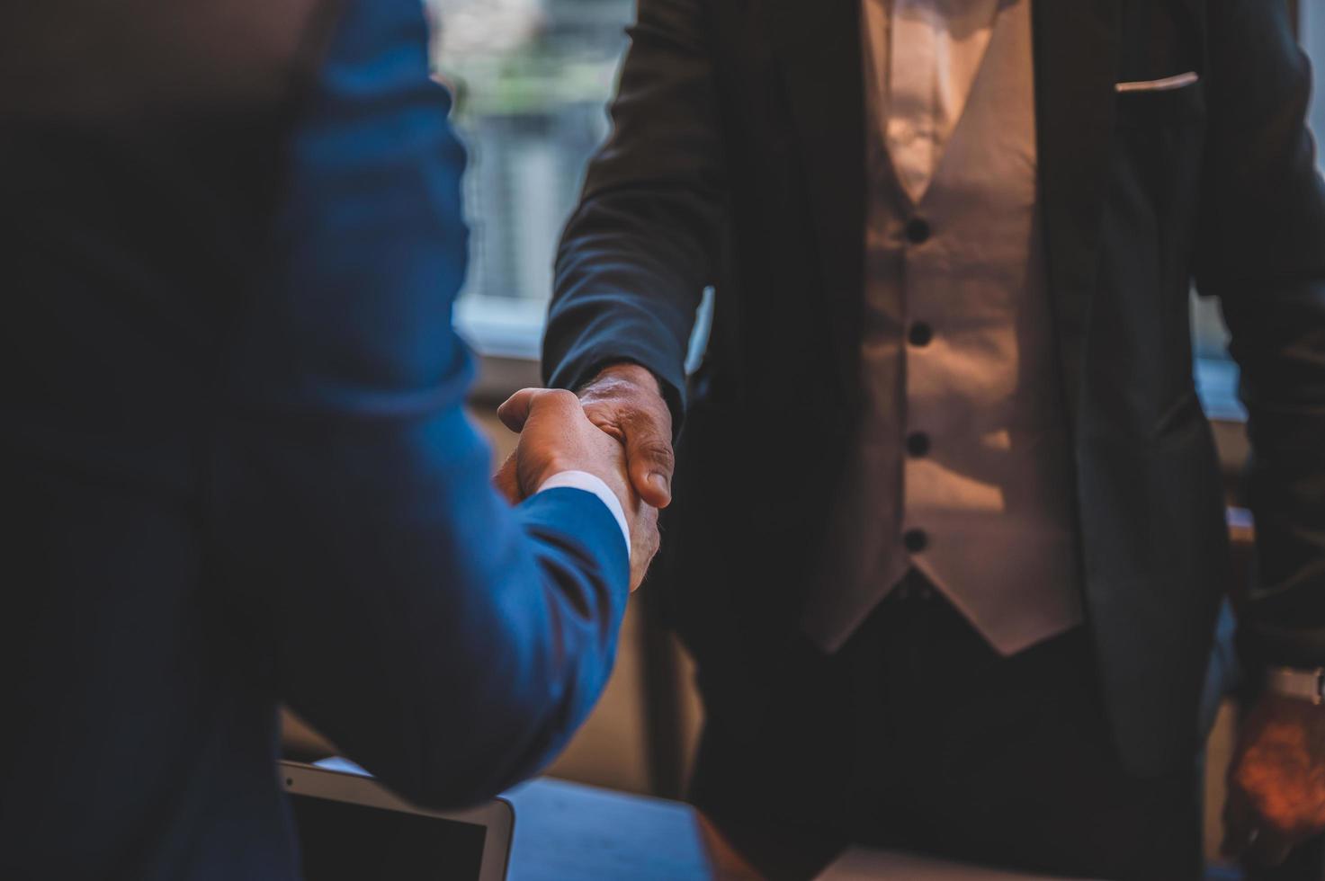 dos hombres en trajes dándose la mano foto