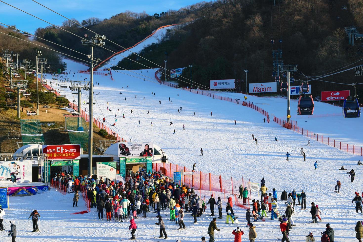 Gente esperando el remonte con gente esquiando en el fondo en el parque Vivaldi Ski World en Corea foto