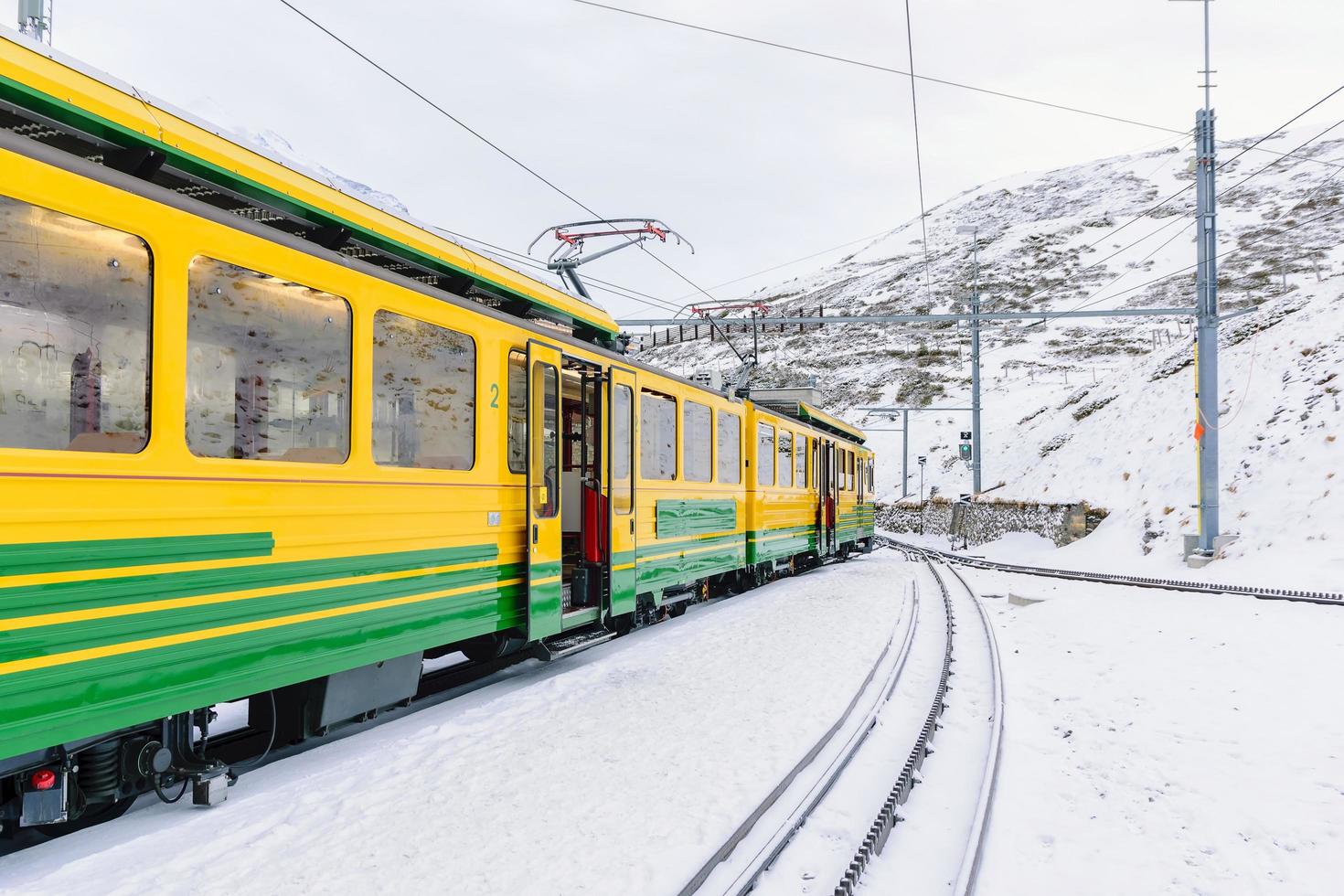 Vagones de tren en el ferrocarril Jungfrau contra montañas nevadas en Suiza foto