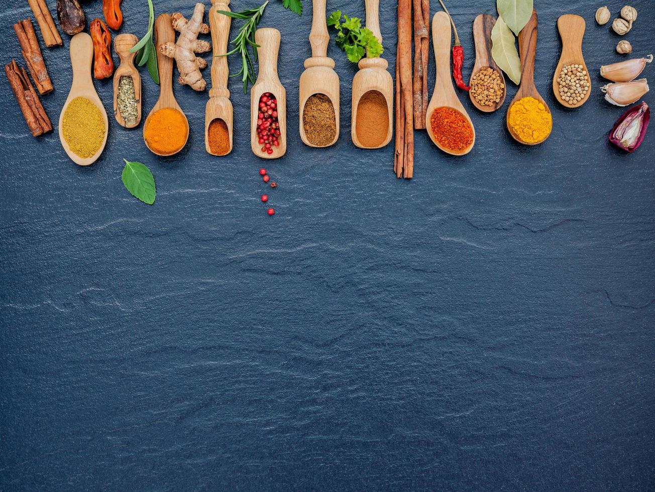 Spices and herbs in wooden spoons with copy space photo