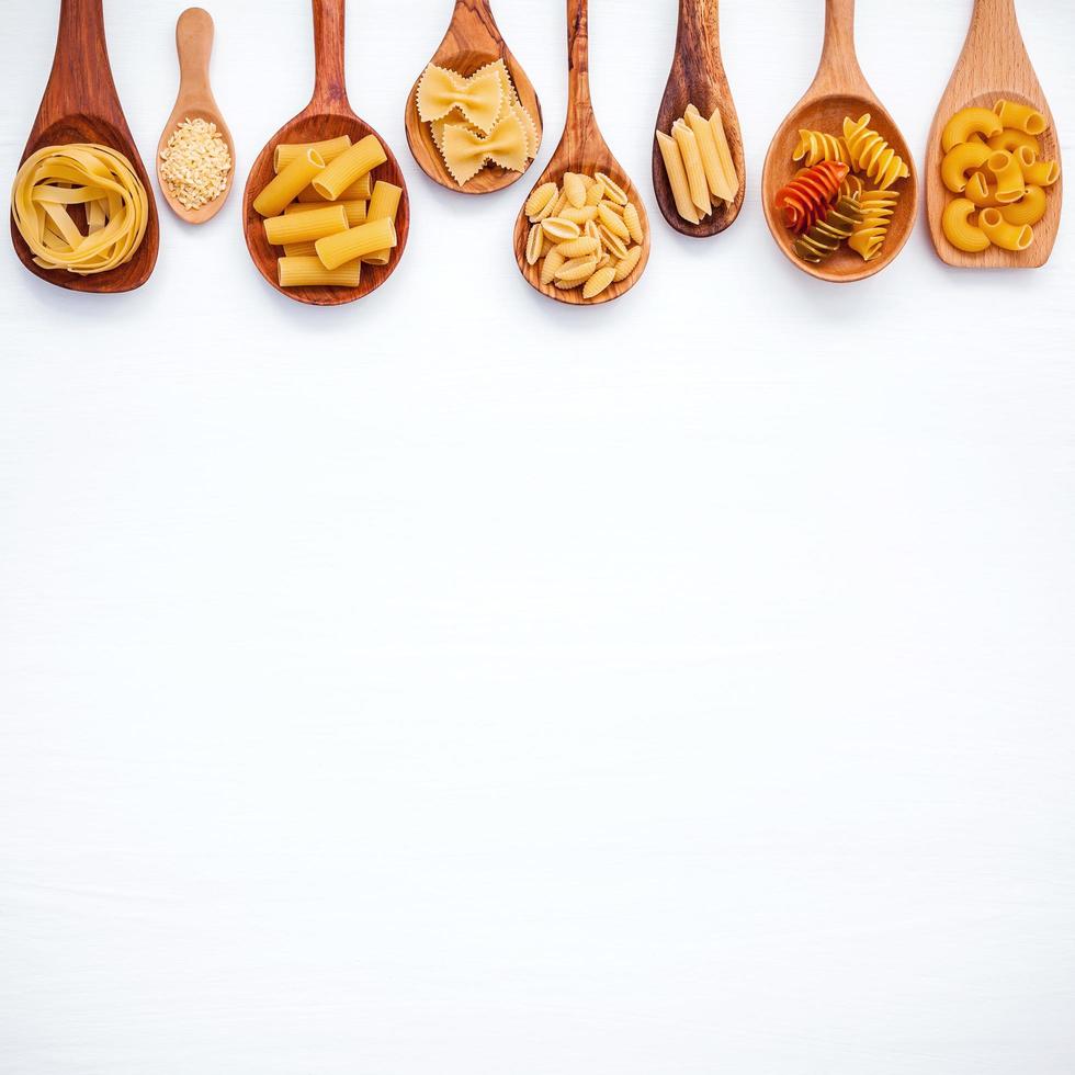 Dried pasta in wooden spoons with copy space photo