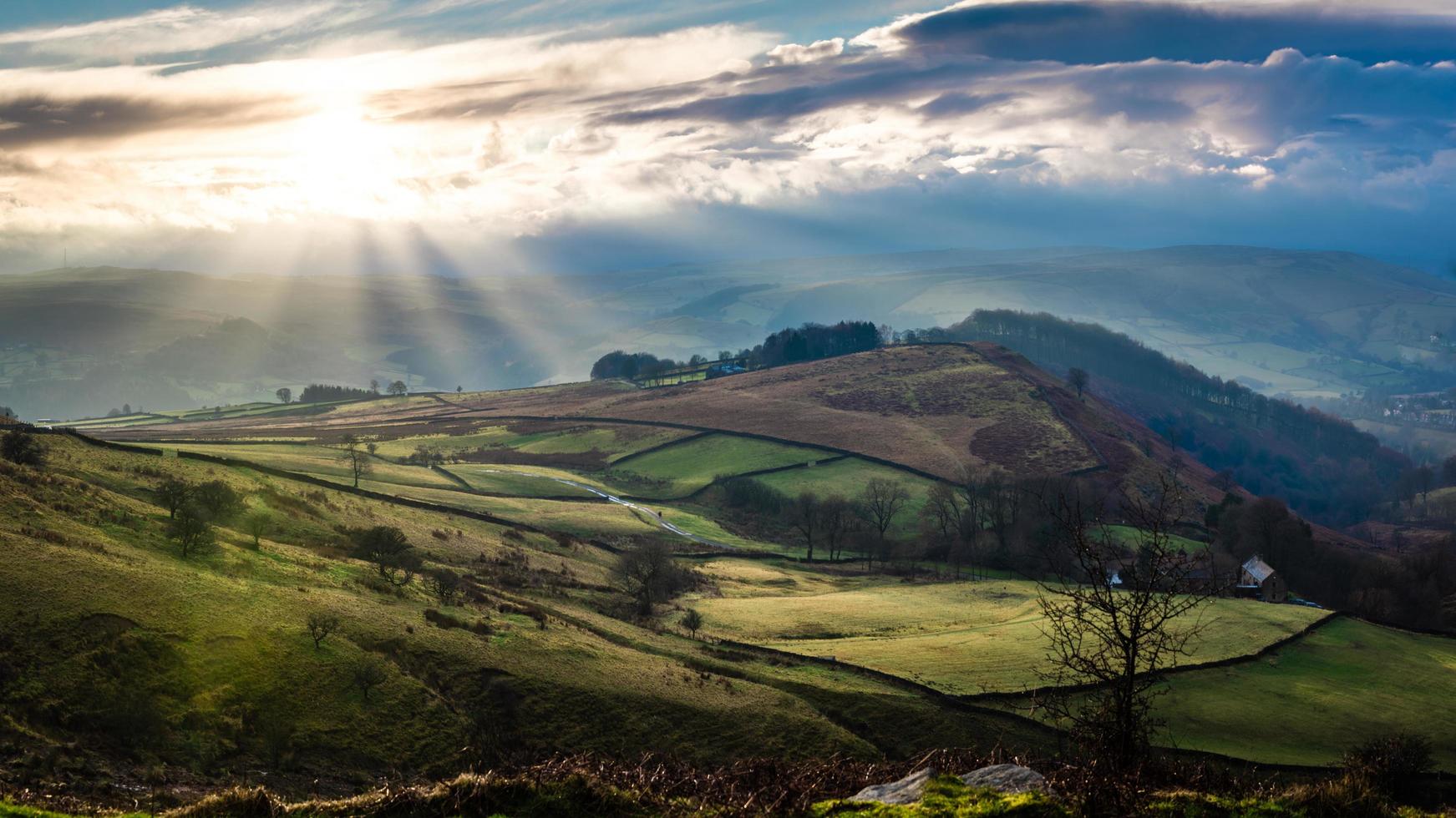 Aerial view of landscape of hills and trees with low sun in a cloudy sky photo