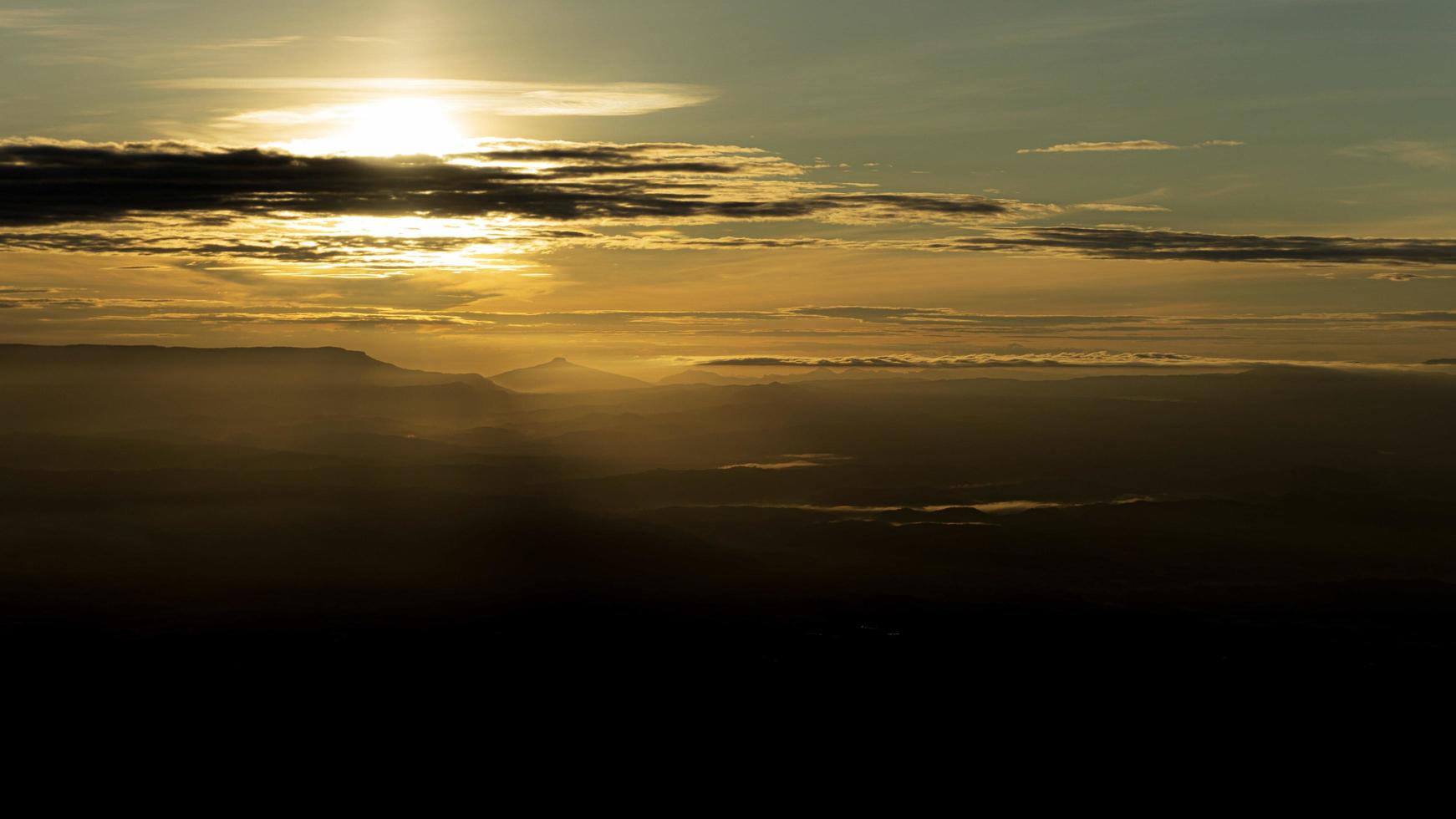 Colorful cloudy sunrise overlooking dark valley photo