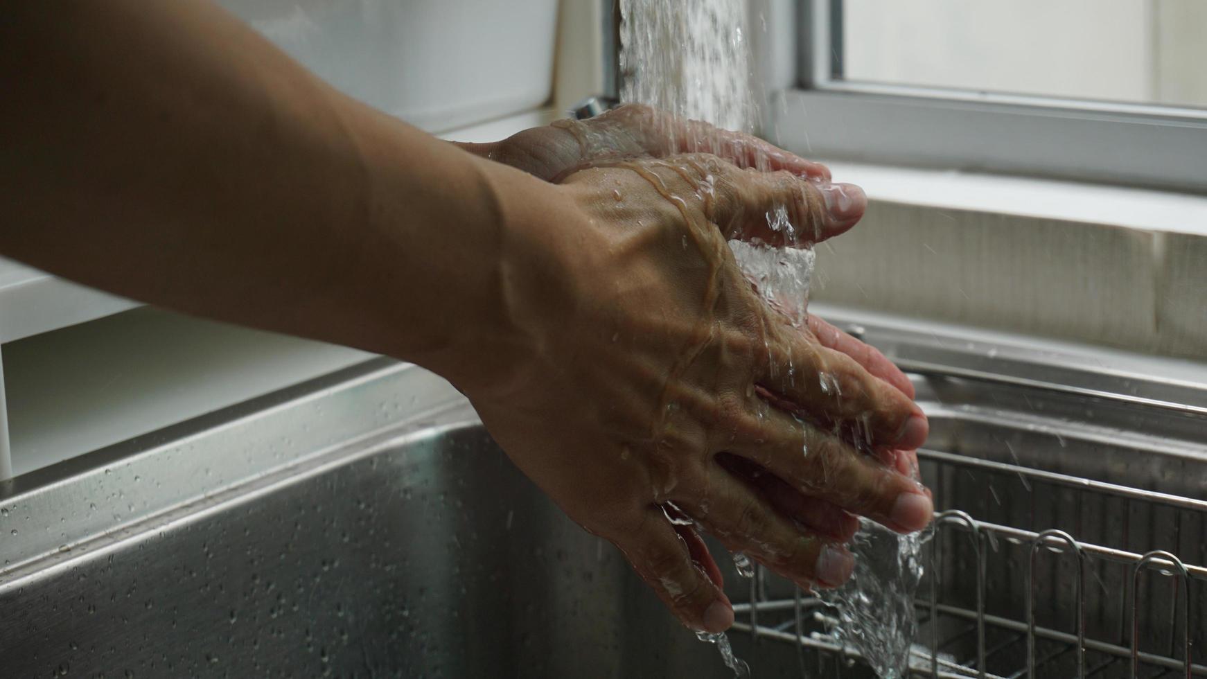 Two hands being washed in a sink by a window photo