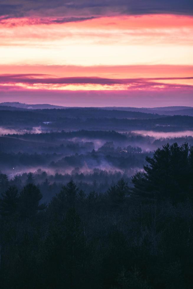 Aerial view of landscape with trees, hills, fog, and mountains with colorful cloudy sunrise photo