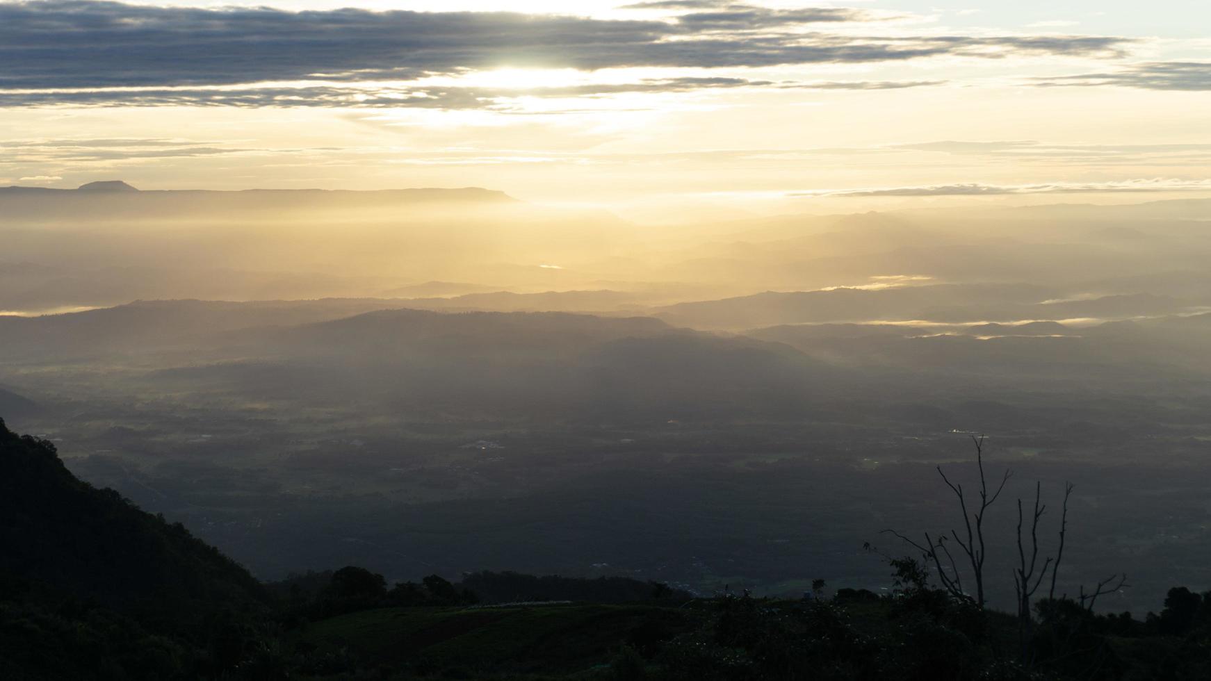 paisaje de valle y montañas con bajo sol en un cielo nublado foto