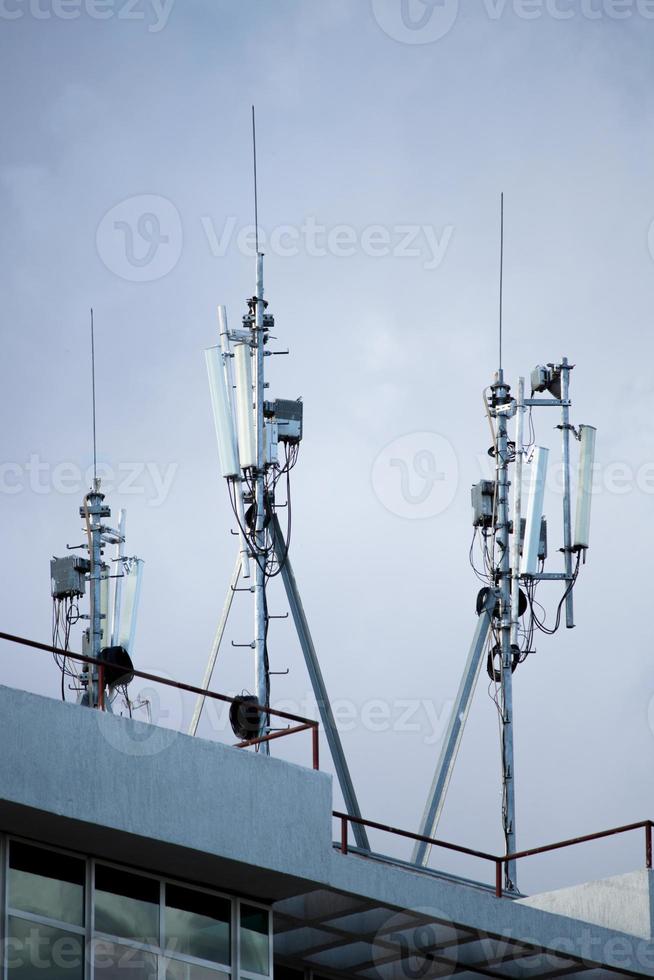 Three cellular tower antennas with cloudy blue sky photo