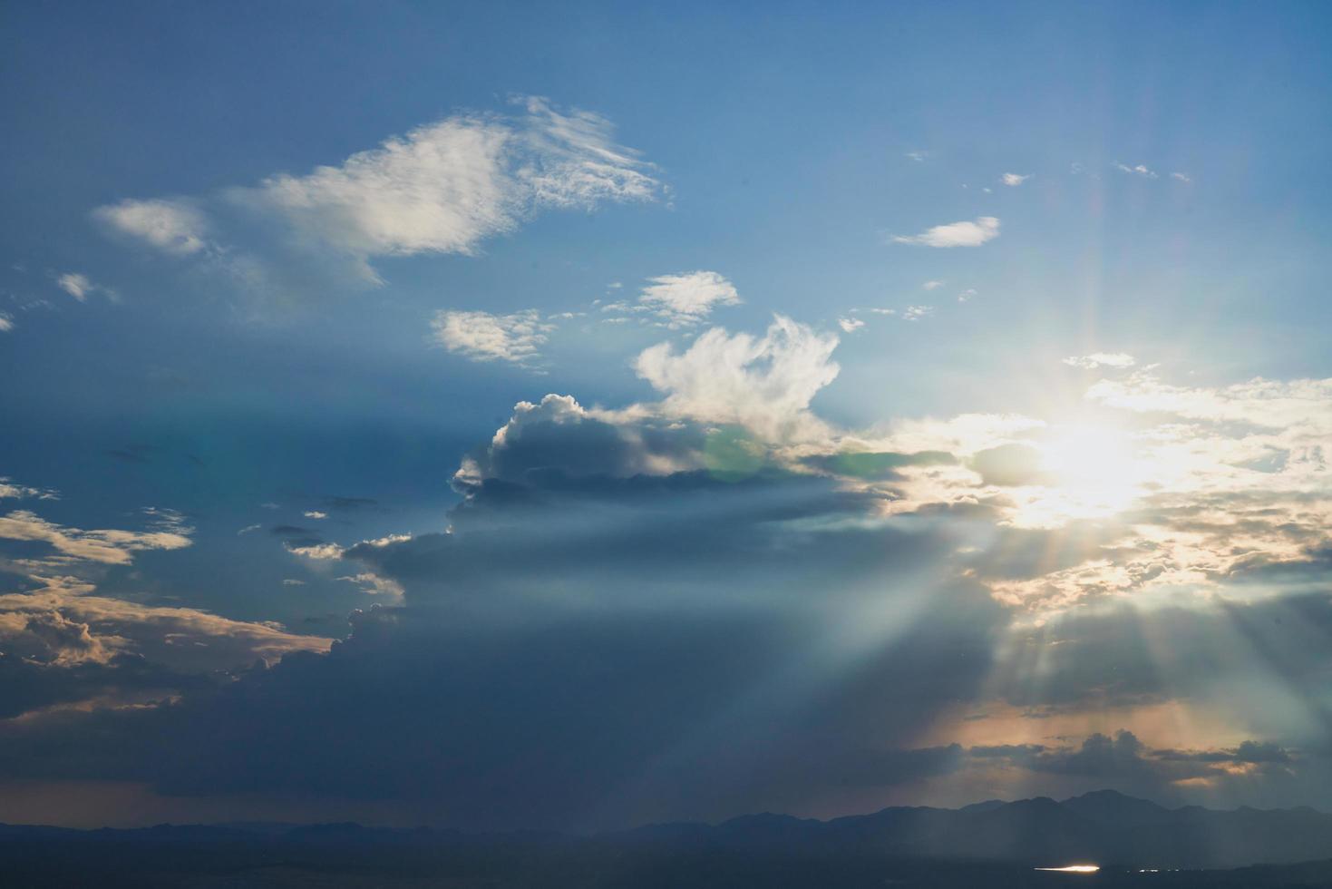 Sun beams in cloudy blue sky photo