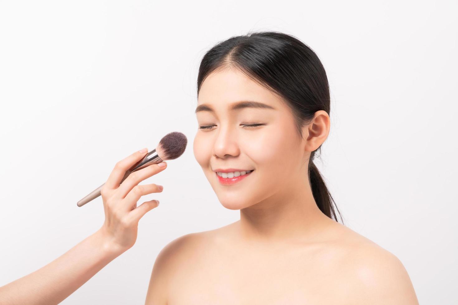 Woman getting makeup done on white background photo