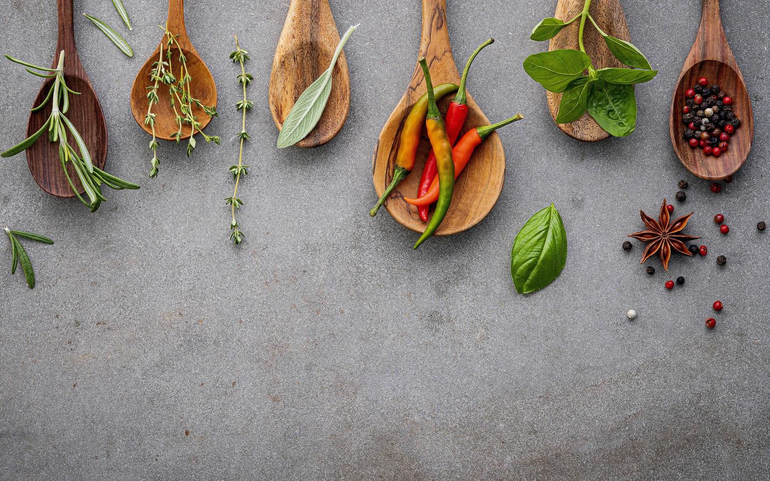 Spices and herbs in wooden spoons on concrete photo