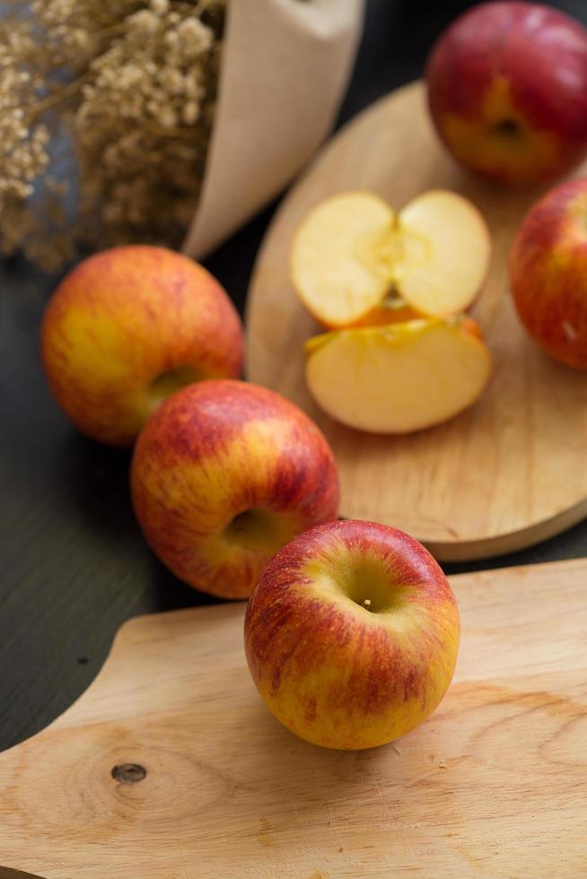 Whole and sliced red apples on wooden cutting boards on black table photo