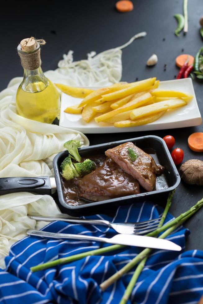 Bistec a la parrilla y brócoli en una sartén con papas fritas foto