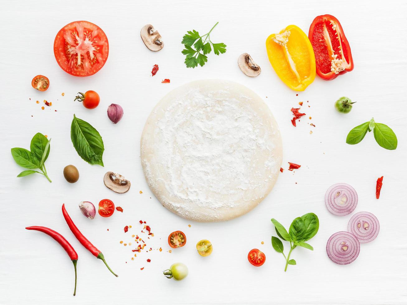 Pizza dough and ingredients on white photo