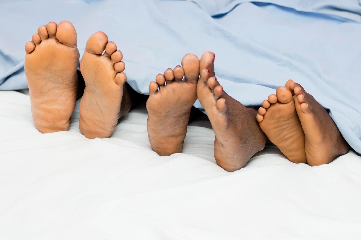 los pies de una familia debajo de las sábanas foto