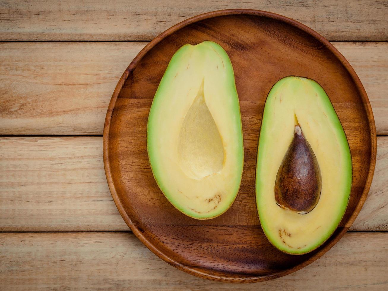 aguacate cortado a la mitad sobre madera foto