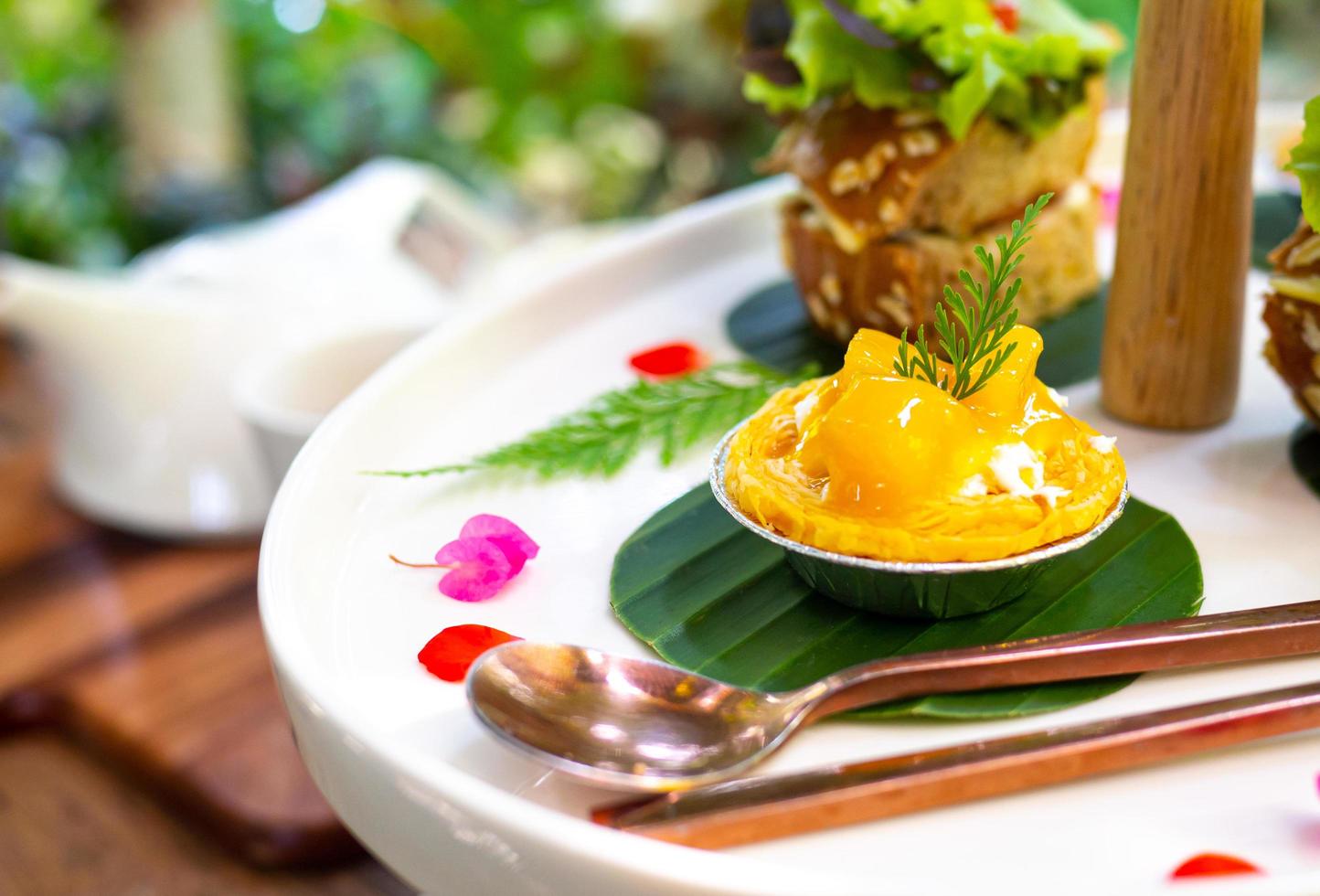 Mango tart mini is served on a white plate and adorned with beautiful flowers photo