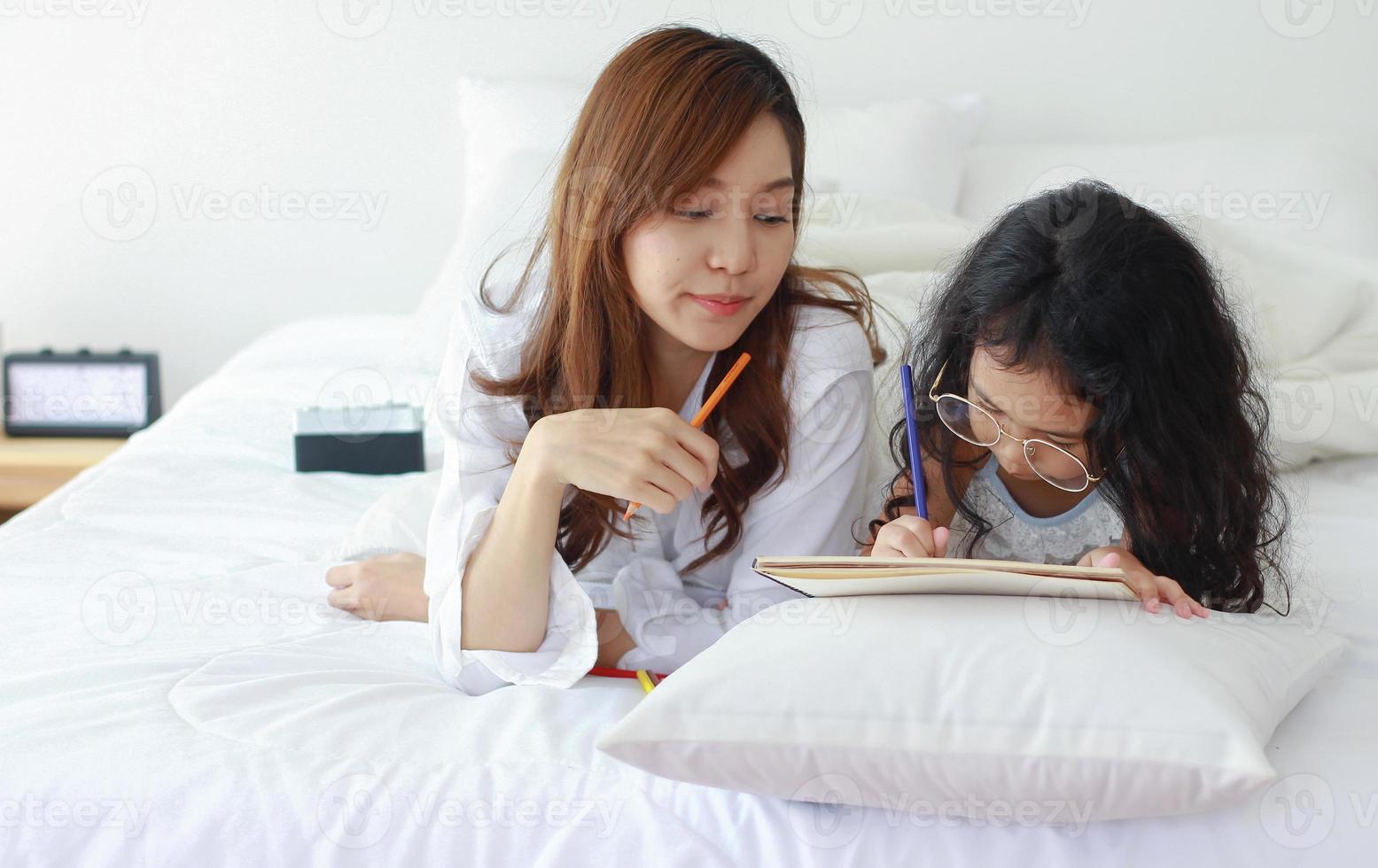 Asian mother and daughter paint together happily on vacation at home photo