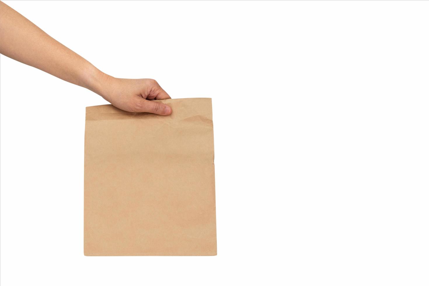 Mockup of a hand holding a recycled craft paper bag isolated on a white background photo