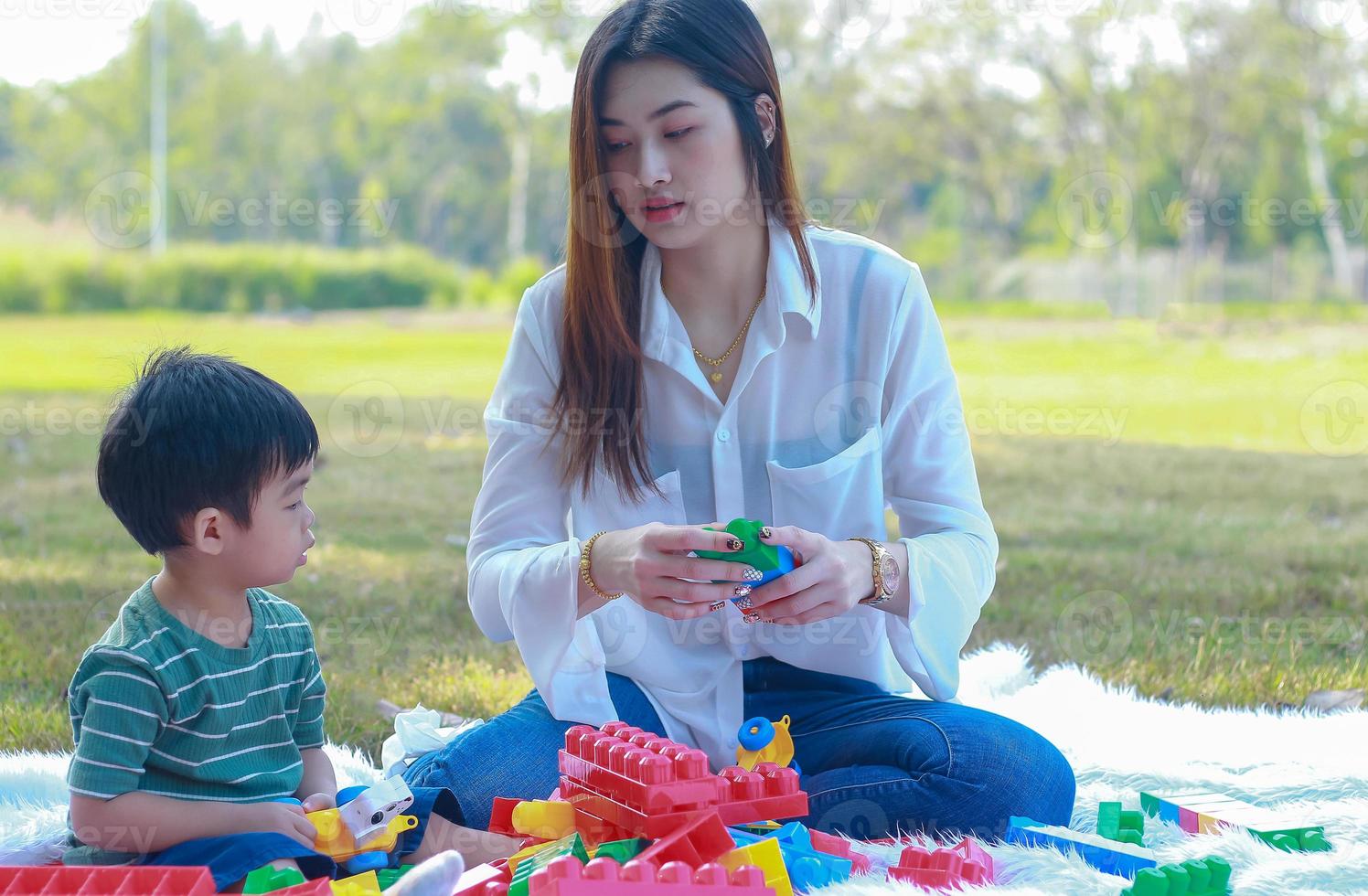 Asian mother and son happily play with toys in the park photo