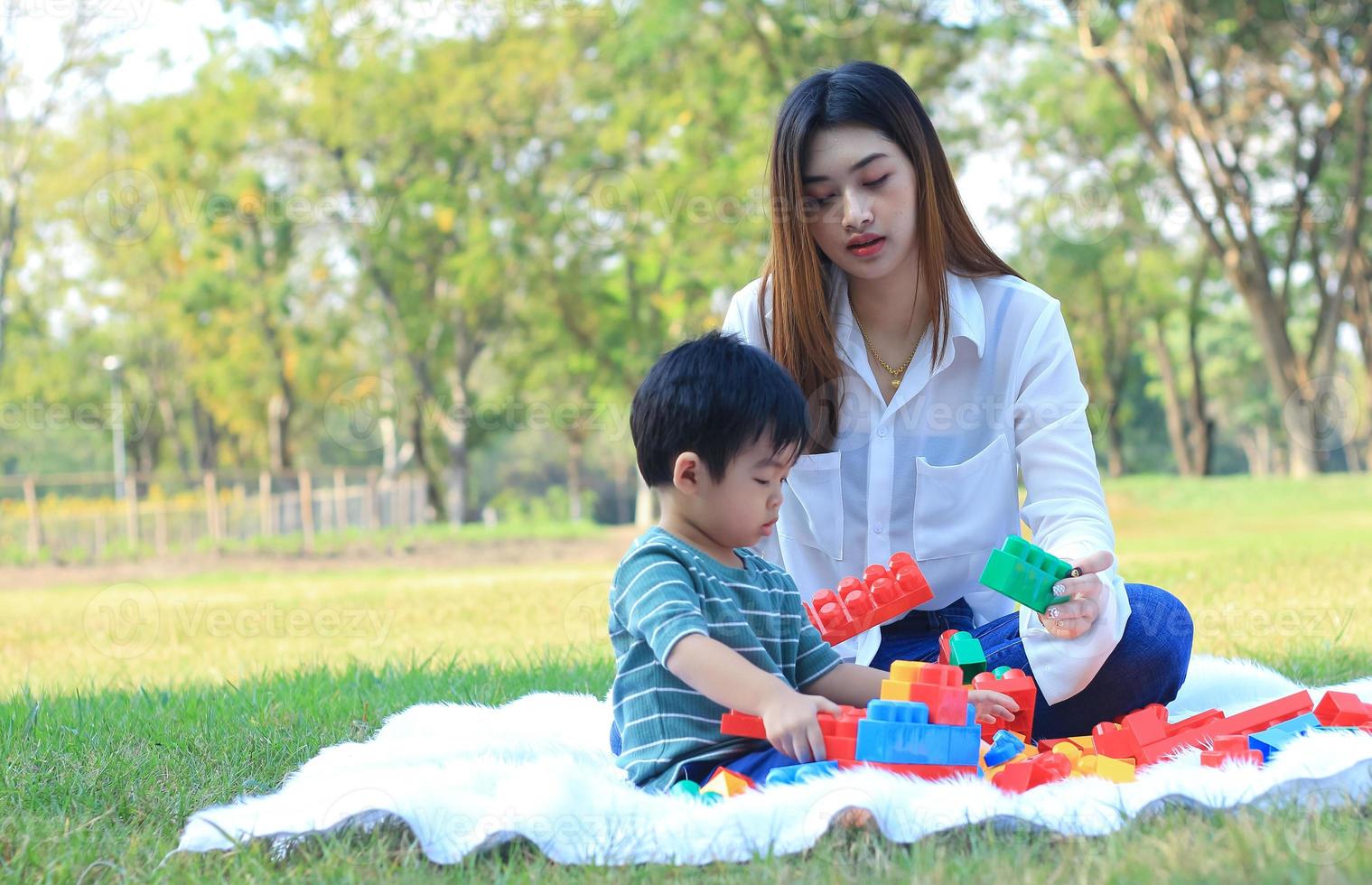 Asian mother and son happily play with toys in the park photo