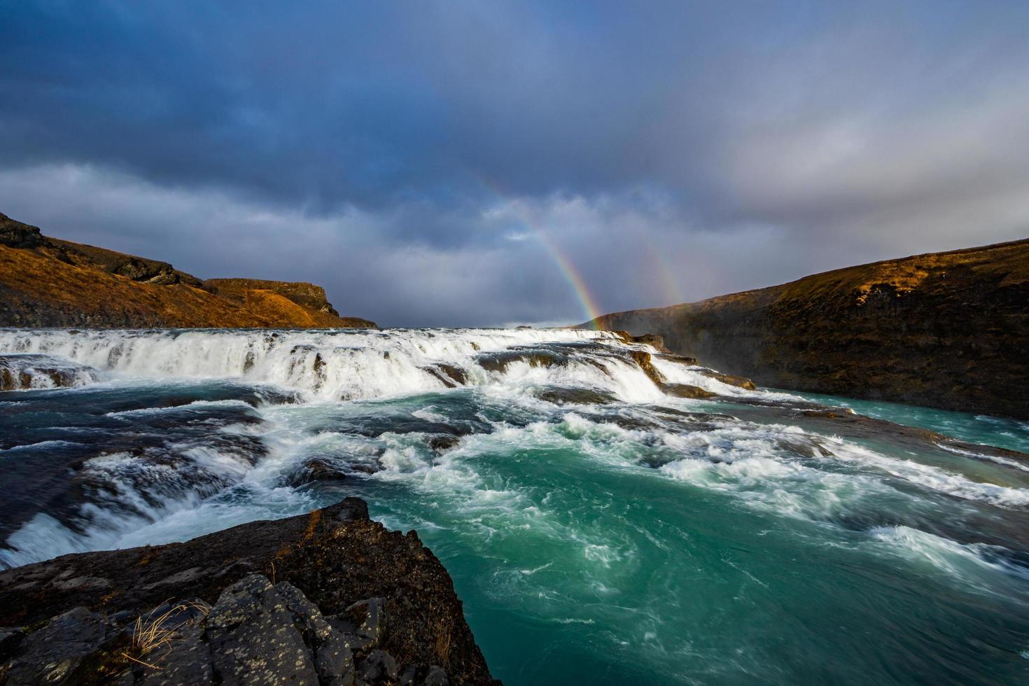 Rainbow and waterfalls against mountain scenery photo