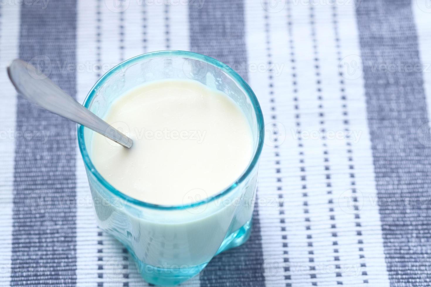 Close up glass of milk and spoon on table photo