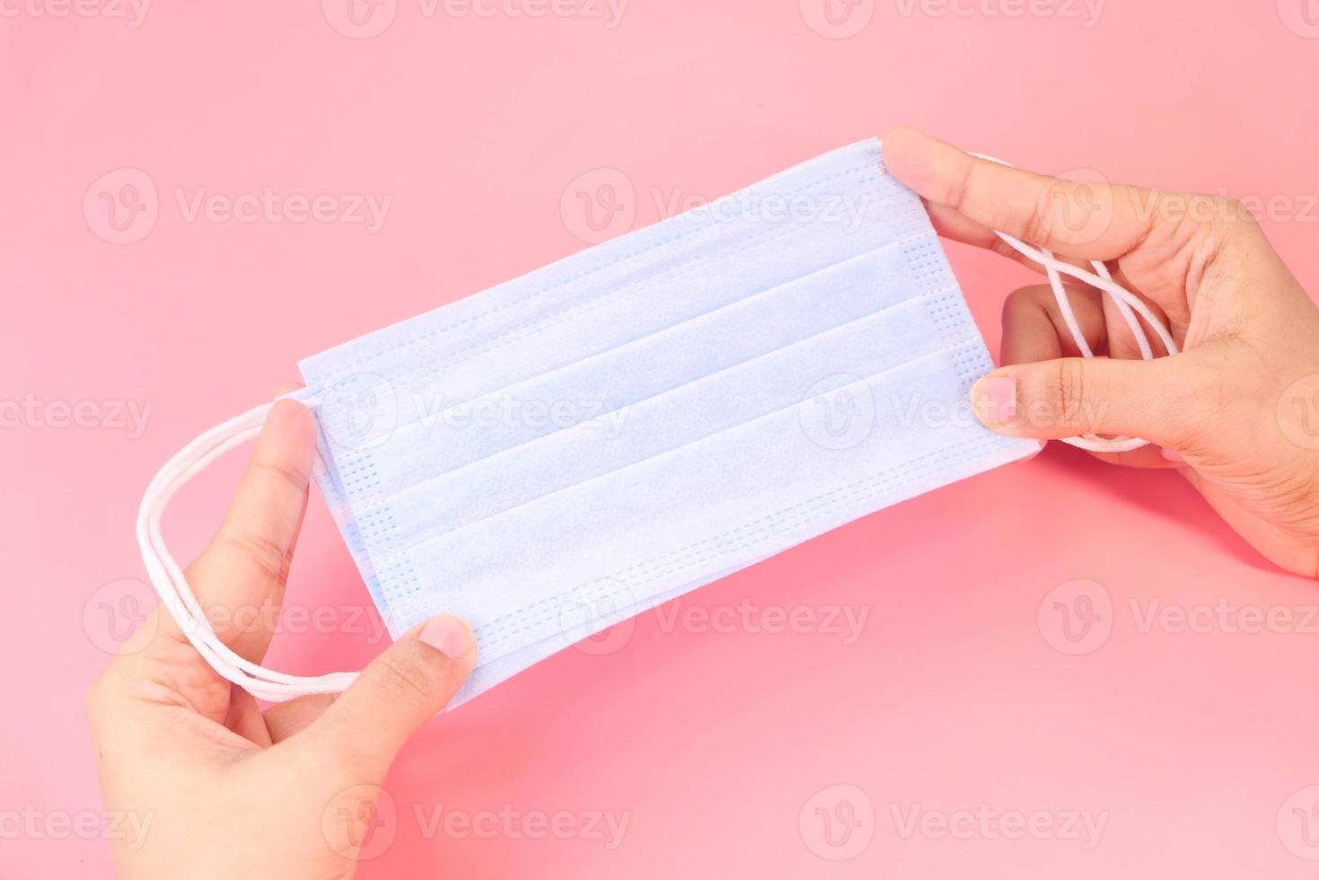 Holding face mask on pink background photo