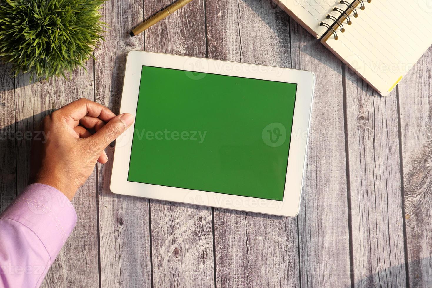 Digital tablet with green screen on wooden background photo