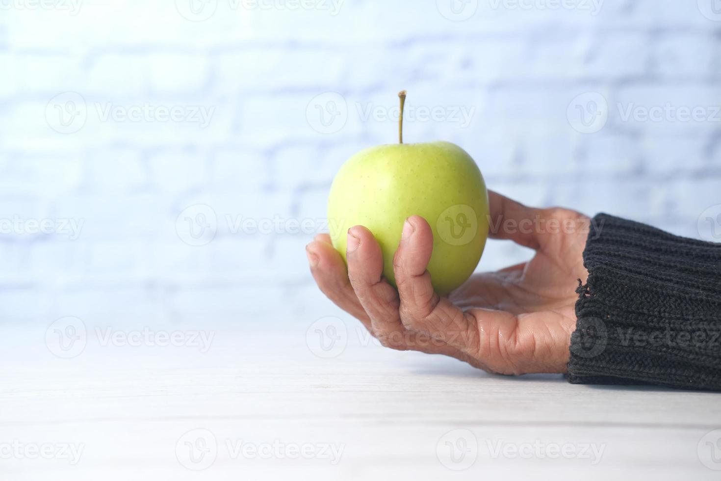 mano que sostiene la manzana verde sobre fondo blanco foto