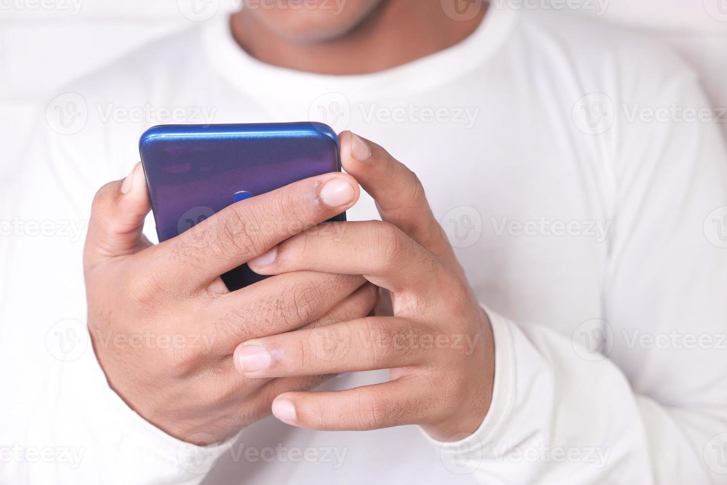 Hombre con camisa blanca jugando en un teléfono inteligente. foto