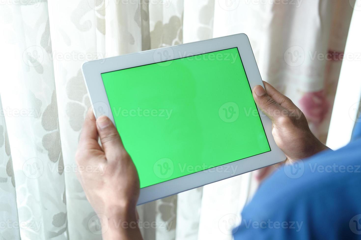 Young man using digital tablet at home with green screen photo