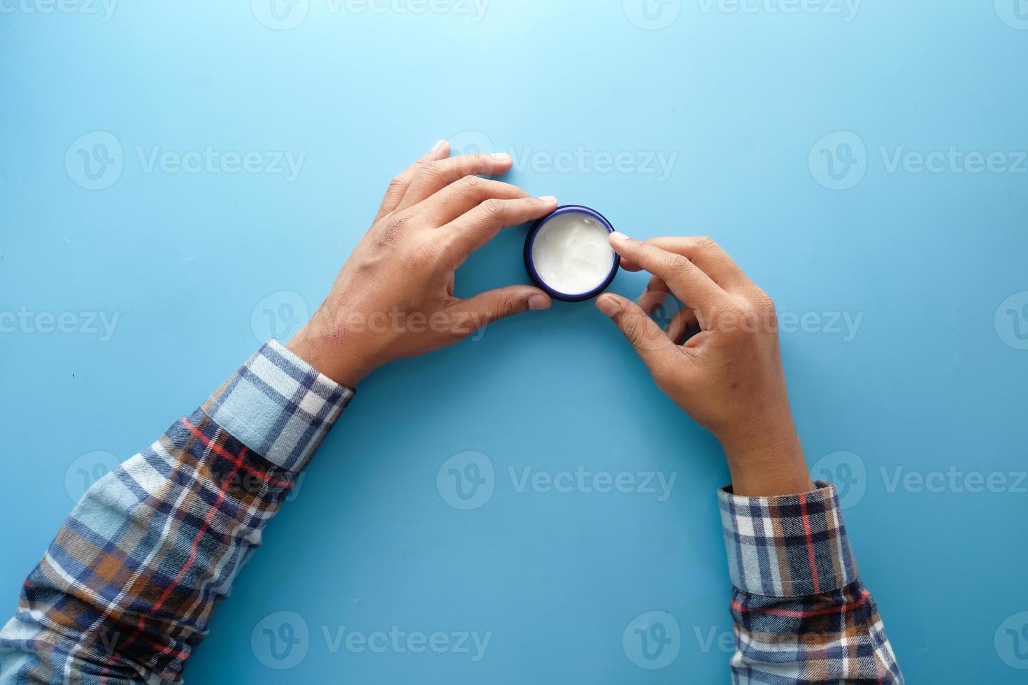 Container with white cream on blue background photo