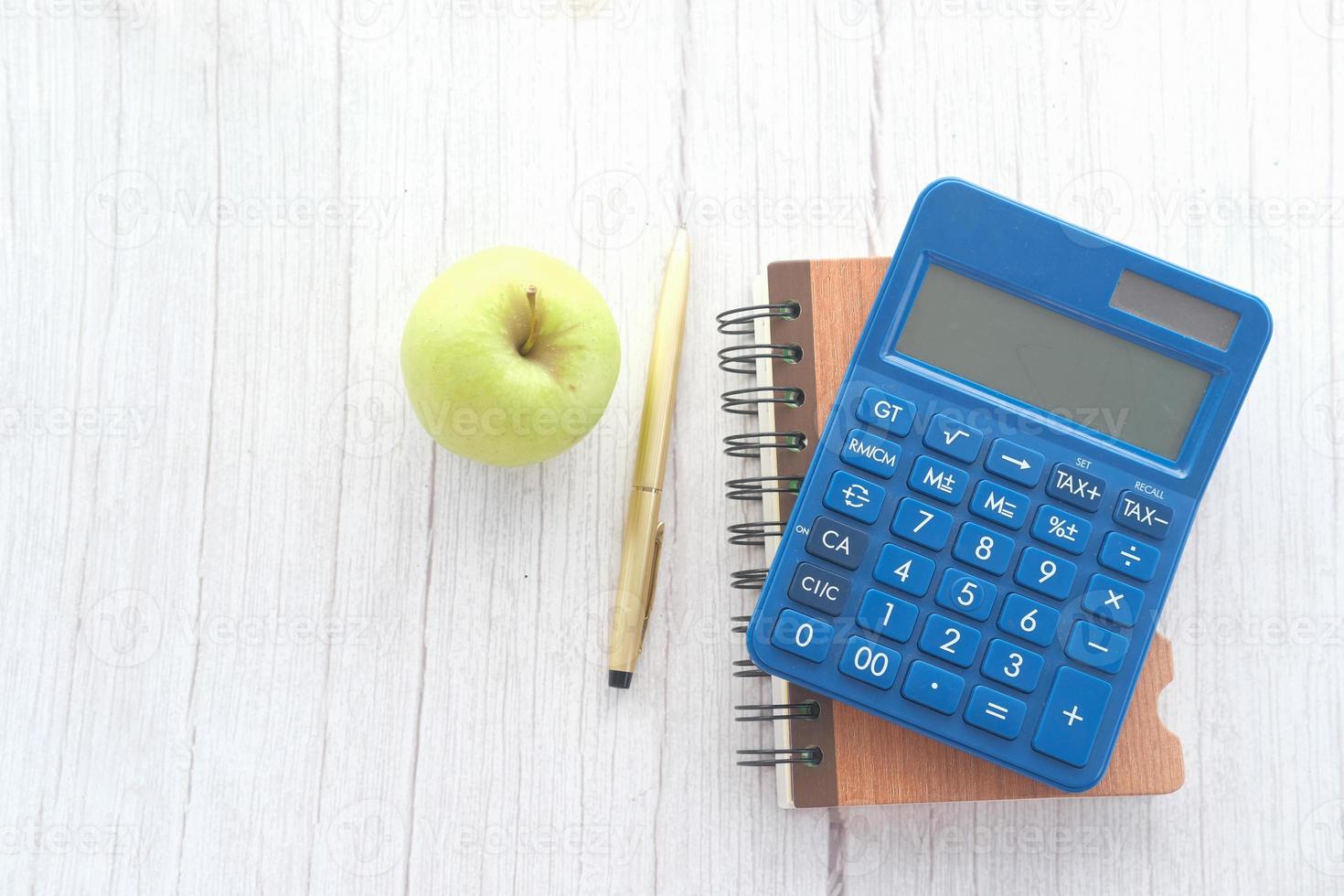 calculadora azul y bloc de notas con manzana verde foto