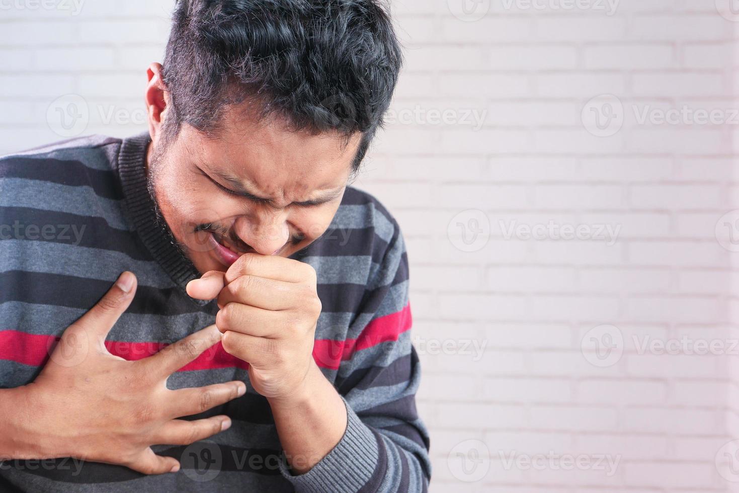 Young asian man coughing and sneezing close up photo