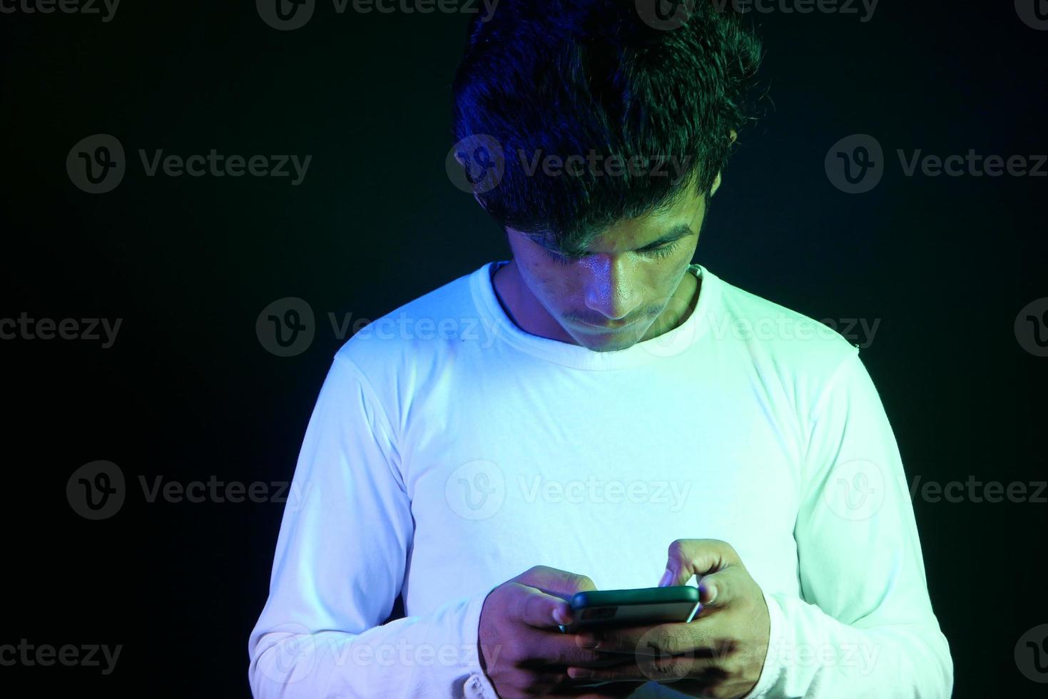 Young man playing on phone with black background photo