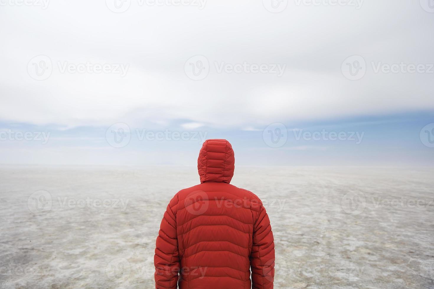 Young man in winter hooded jacket at Salar de uyuni salt flat in Bolivia photo