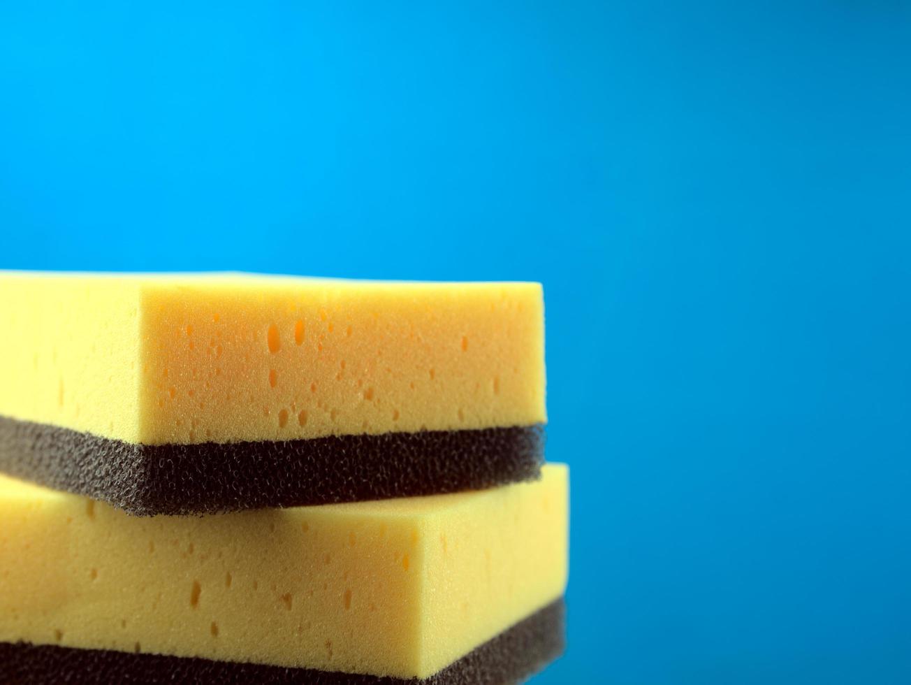 Yellow and black scouring pad sponges isolated with a blue background photo