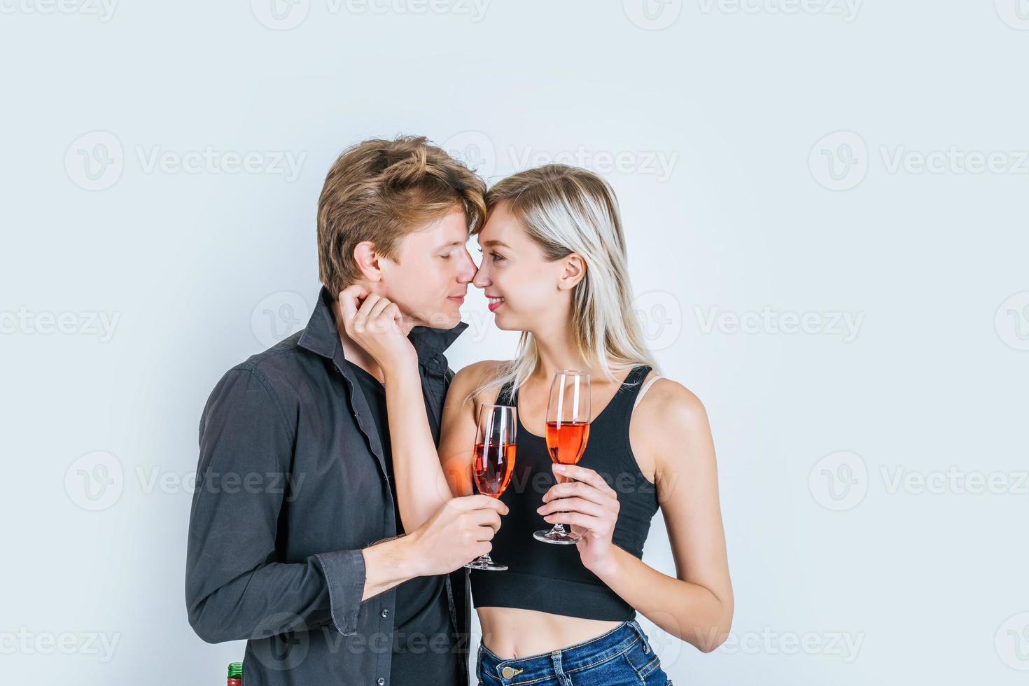 Portrait of happy young couple drinking wine in studio photo
