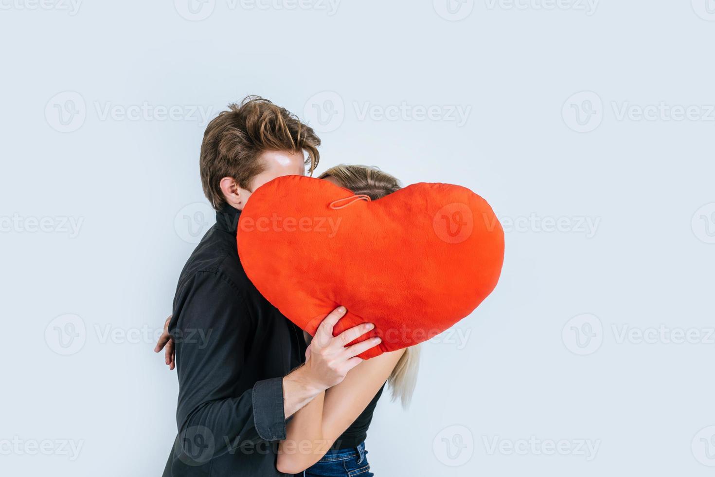 feliz pareja amorosa juntos sosteniendo un corazón rojo foto