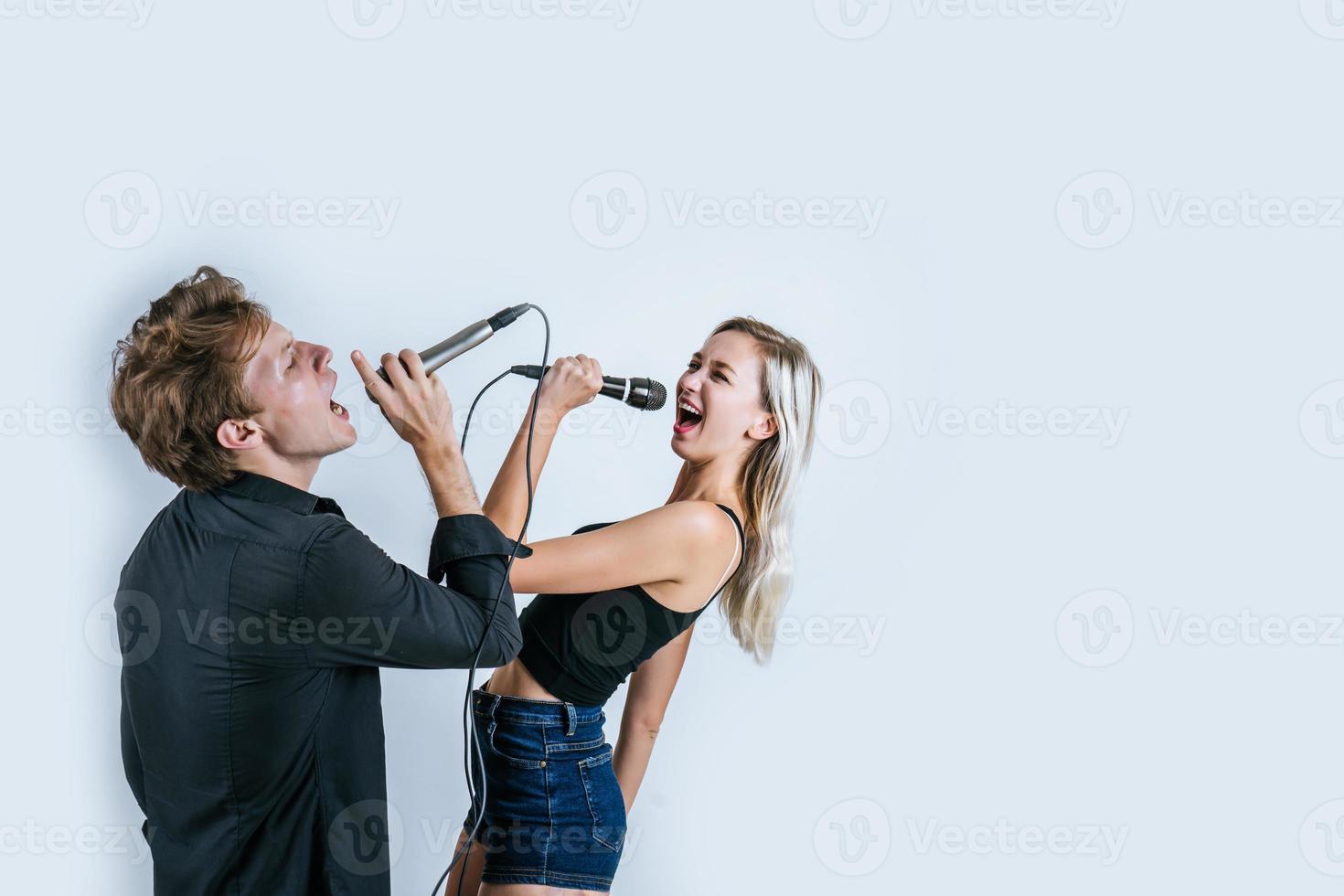 feliz retrato de pareja sosteniendo micrófonos y cantando foto