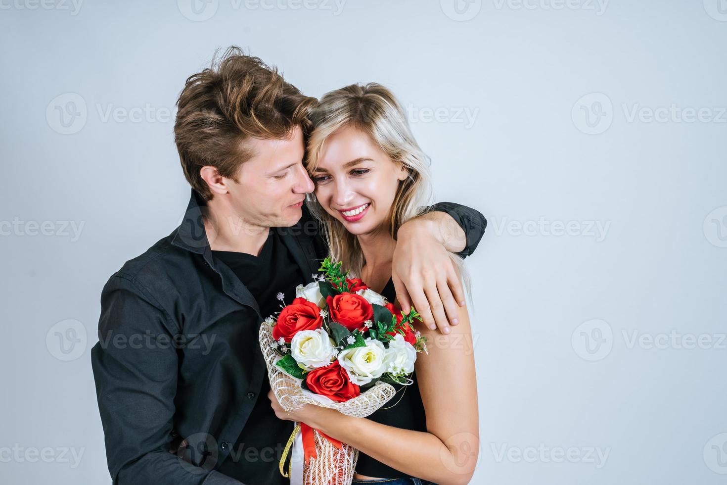 Portrait of happy young couple with flowers in studio photo