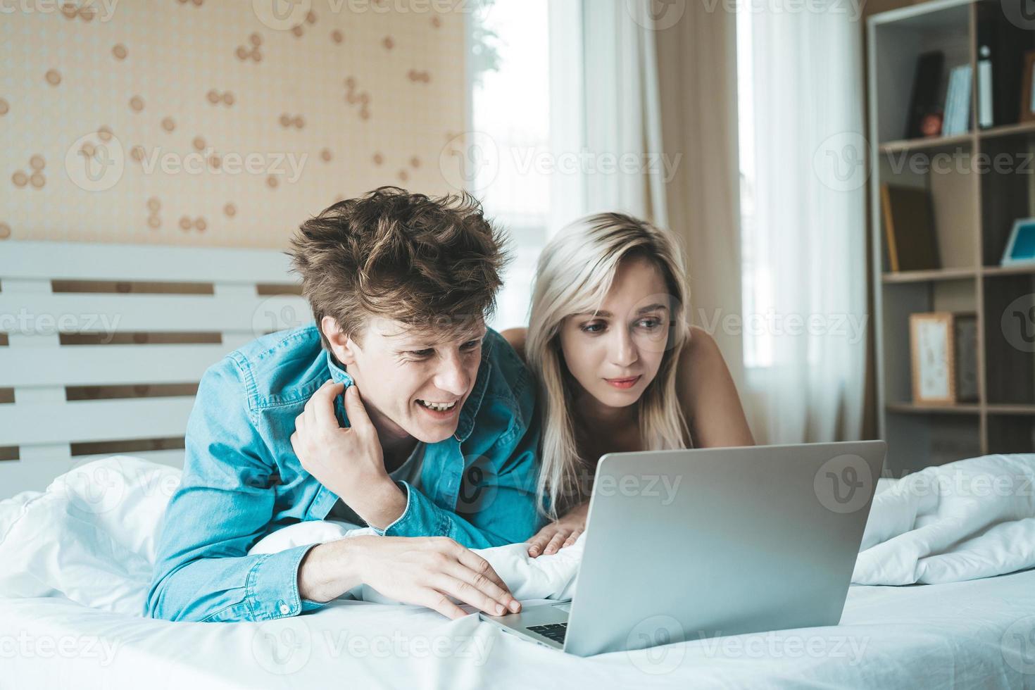 pareja feliz, usar la computadora portátil, computadora portátil, en la cama foto