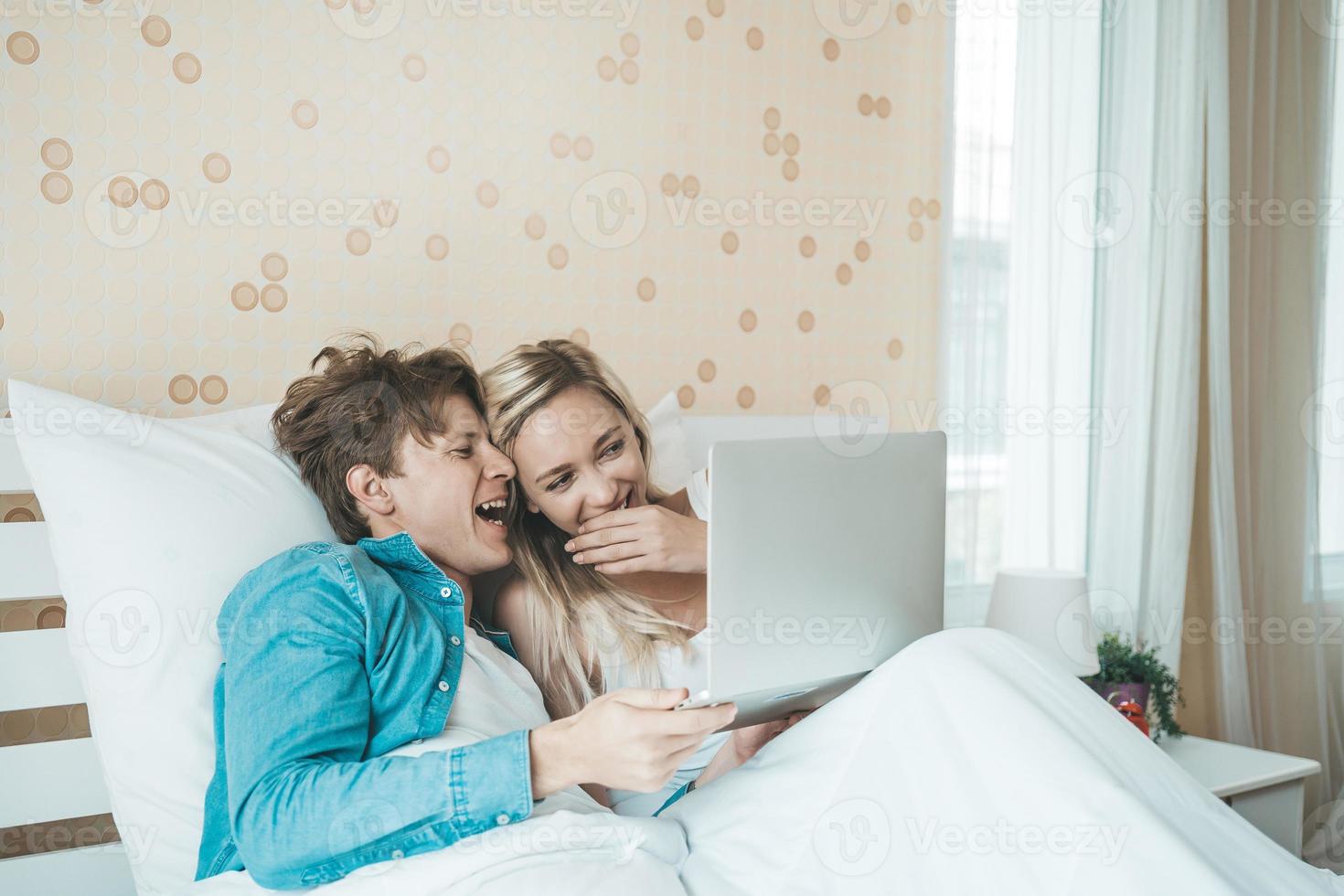 pareja feliz, usar la computadora portátil, computadora portátil, en la cama foto