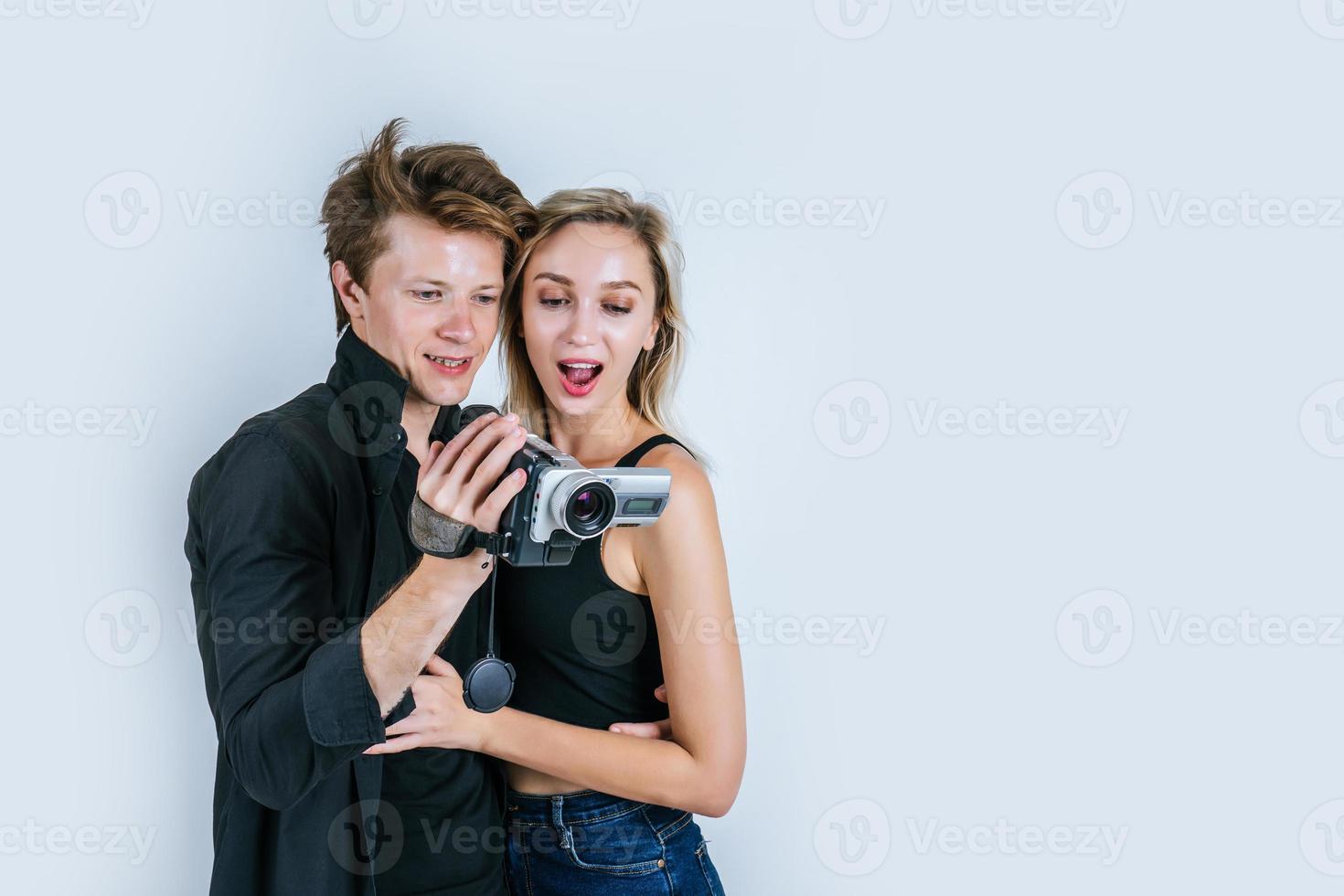 Happy portrait of couple holding video camera and recording a video photo