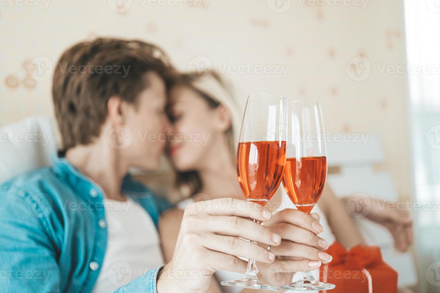 pareja feliz bebiendo vino en el dormitorio foto