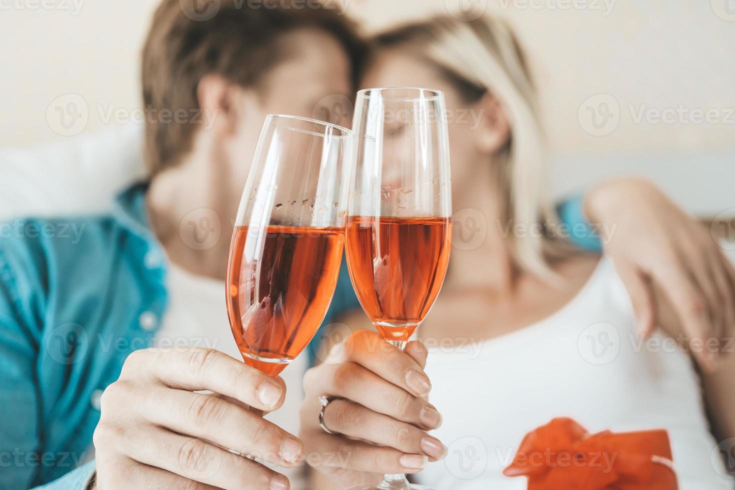 Happy couple drinking wine in the bedroom photo