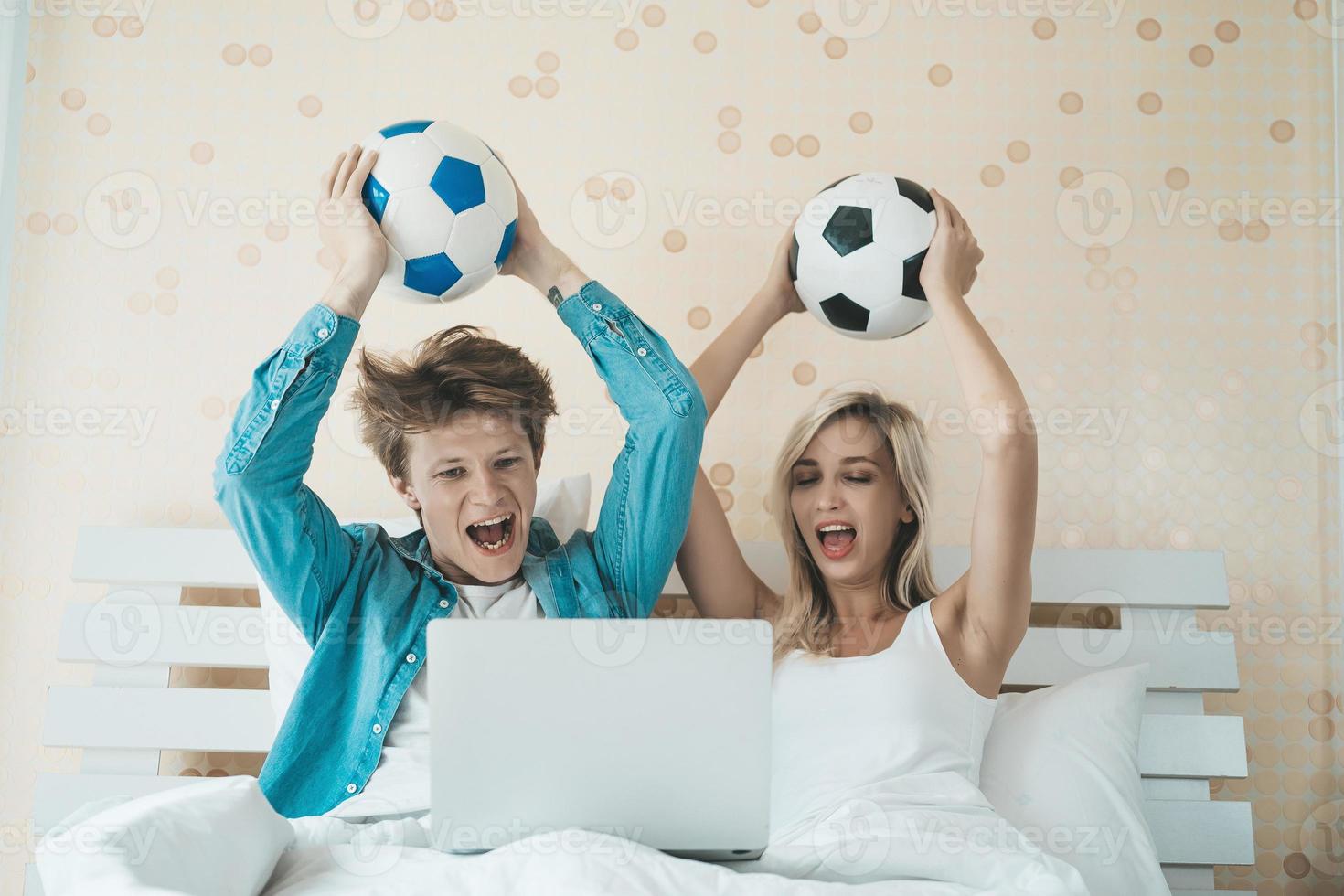 Happy couple watching soccer football on the bed photo