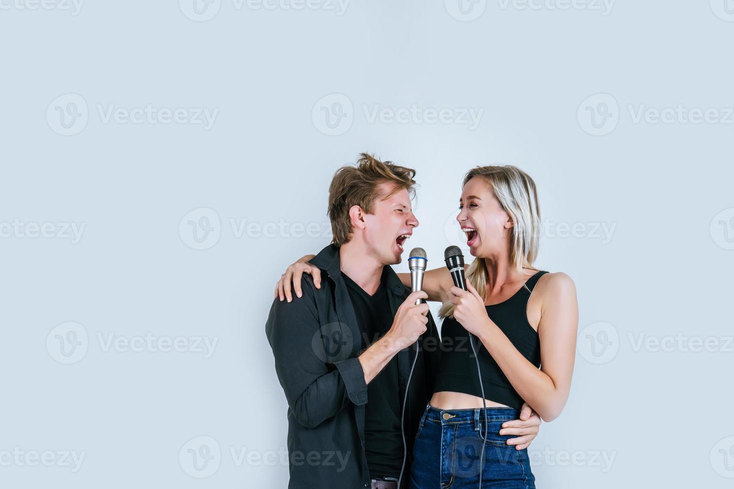 feliz retrato de pareja sosteniendo micrófonos y cantando foto